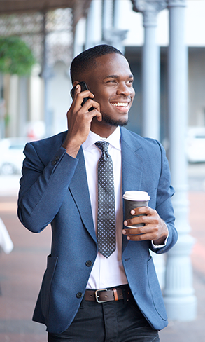 Business man smiling and walking outside while talking on cellphone 